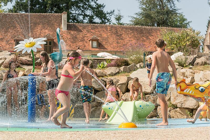 [Translate to Allemand:] des familles qui jouent dans l'espace aquatique d'un camping de luxe