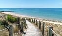 [Translate to Allemand:]  A scenic wooden boardwalk with rope railings cutting through sand dunes, near a luxury Les Castels campsite